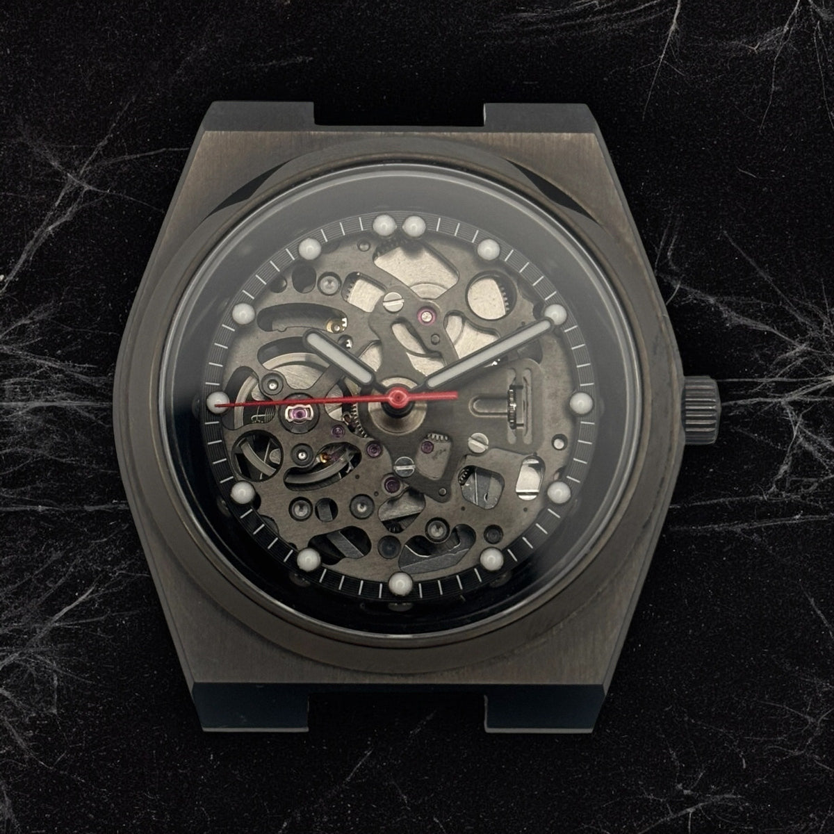 Black mechanical watch on a dark marble background with no strap attached