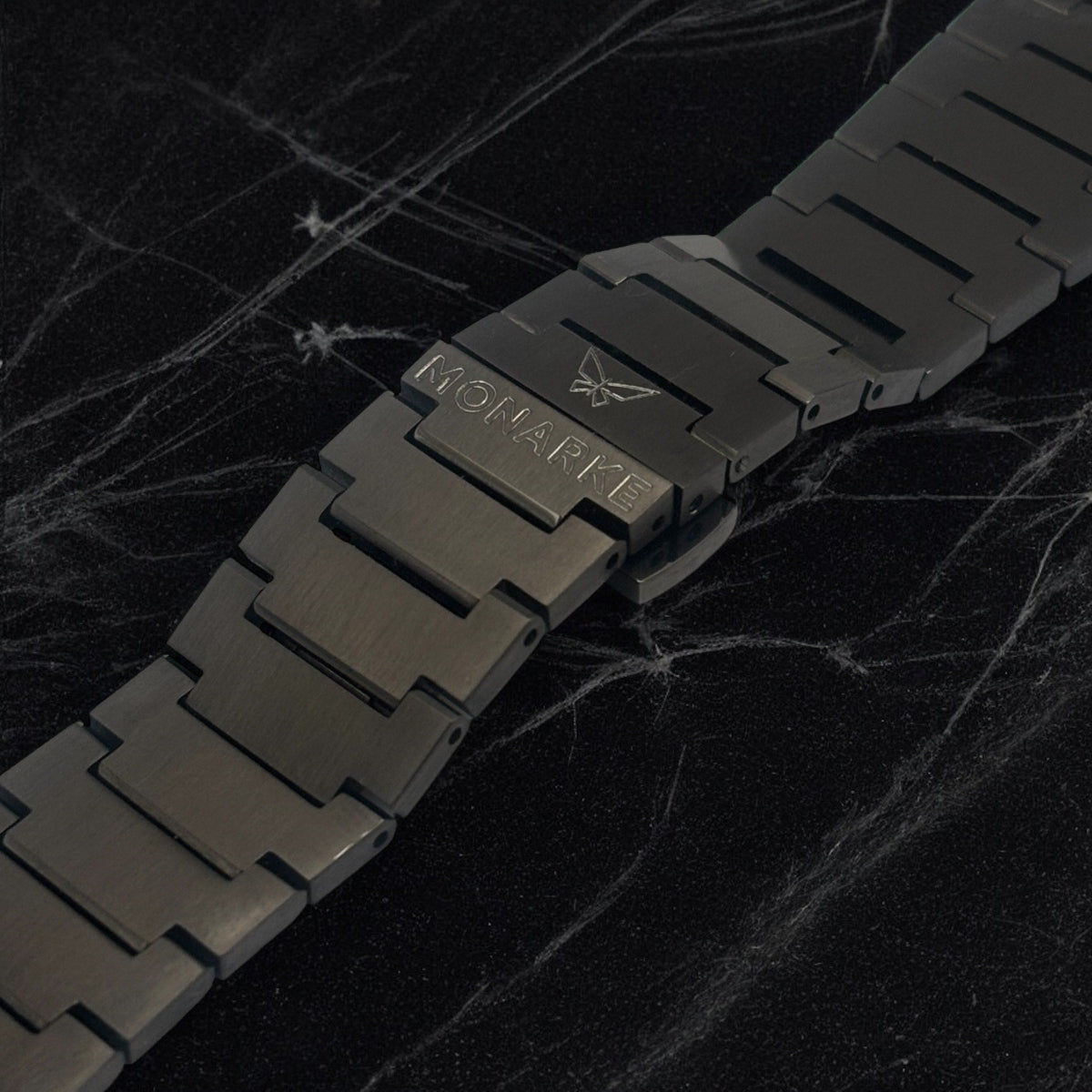 Black metal watch strap on a dark marble background