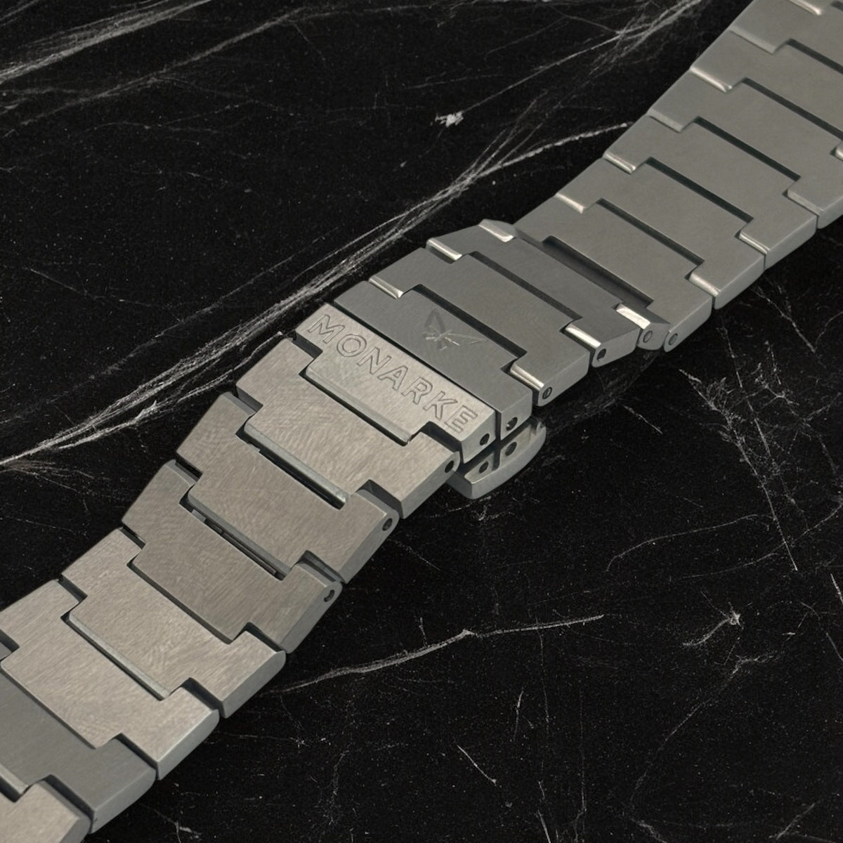 Silver metal watch strap on a dark marble background