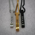 Three necklaces (silver, black and gold) with bar pendants displaying 'MNRK' branding on a grey counter.