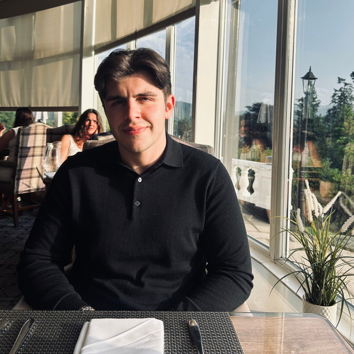 Man sitting at a table with large windows in the background