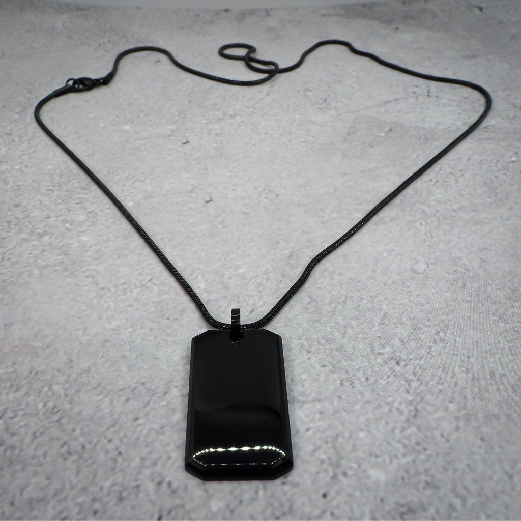 Black rectangular pendant on a chain on a grey counter.