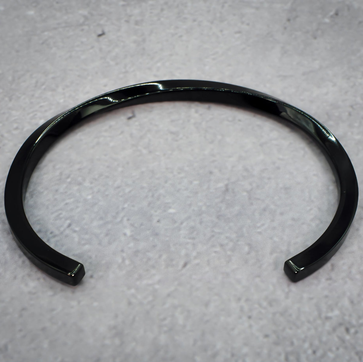 Black metal bracelet on a grey counter.