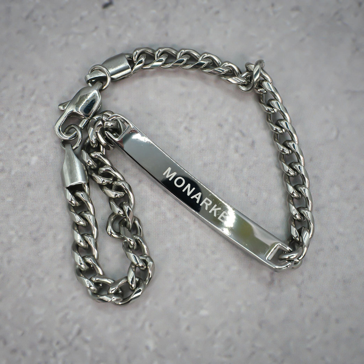 Silver chain bracelet with 'MONARKE' tag on a grey background.