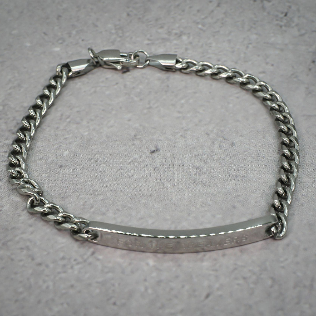 Silver chain bracelet evenly spread out on a grey background
