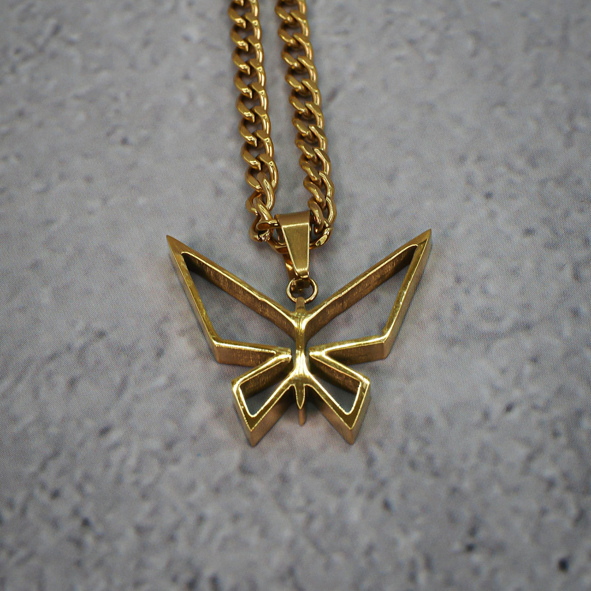 Gold butterfly pendant necklace on a grey counter.