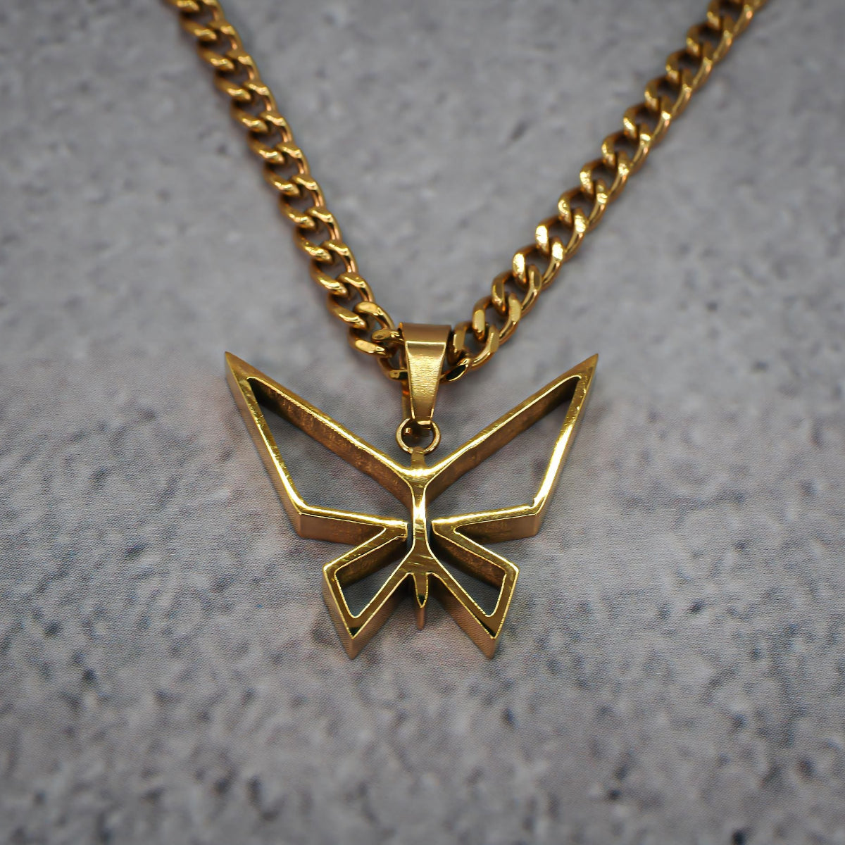 Gold butterfly pendant necklace on a grey counter.