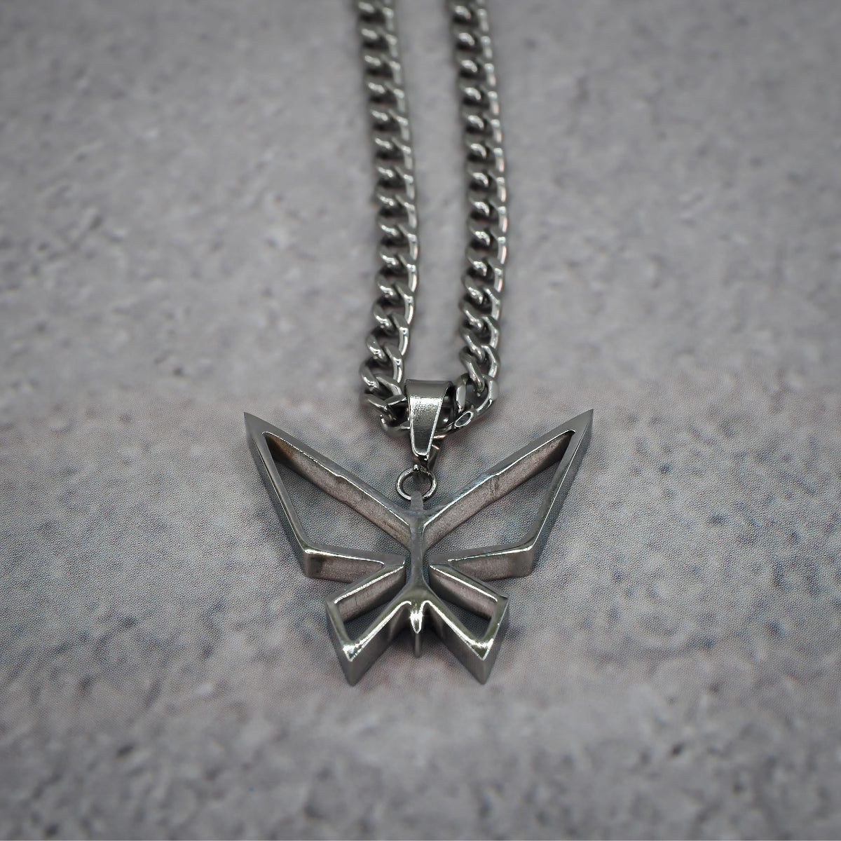 Silver butterfly pendant necklace on a grey counter.