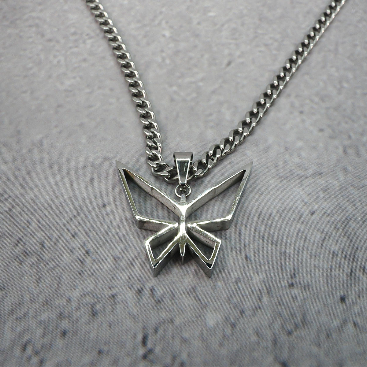 Silver butterfly pendant necklace on a grey counter.