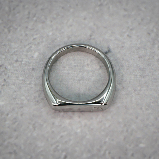 Top down view of a silver ring with left aligned butterfly logo on a grey counter